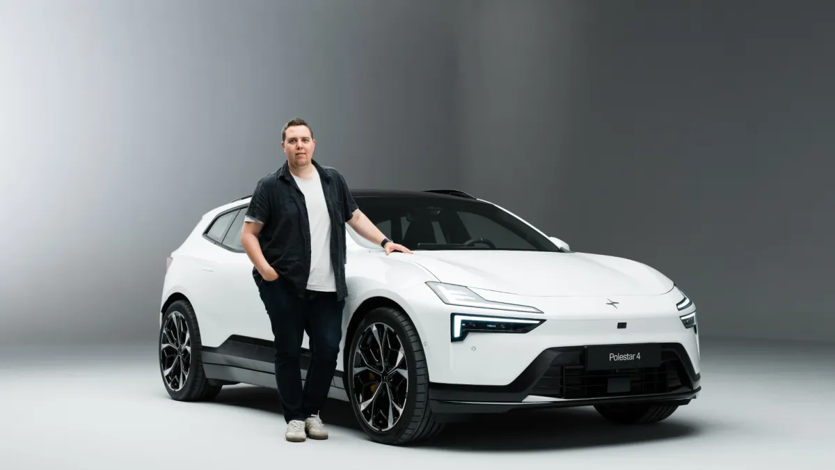 Christoffer Gullin, grundare av Bonize Digital AB, står bredvid en vit elbil i en ljusgrå fotostudio